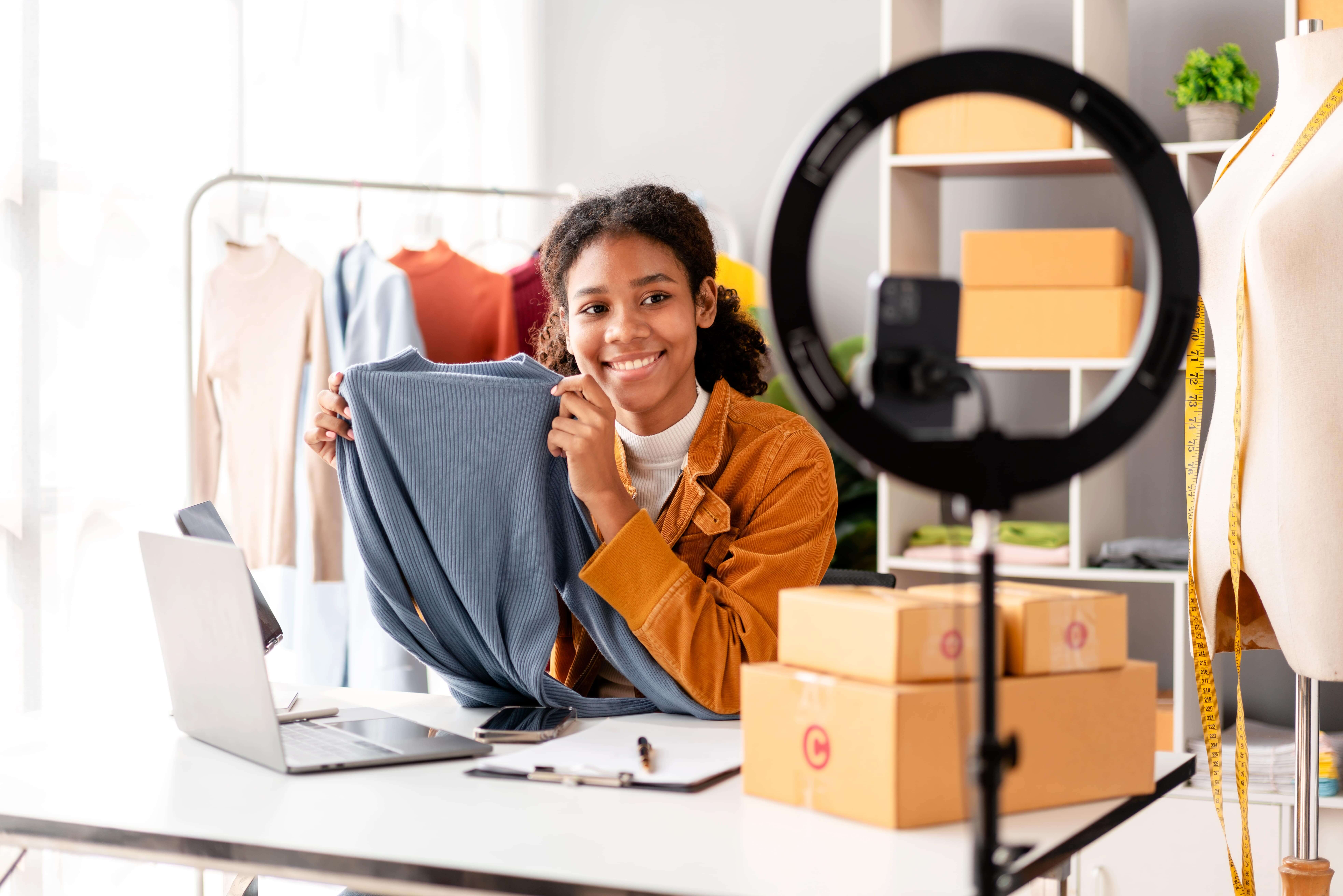 Female e-commerce influencer filming new clothing she just received