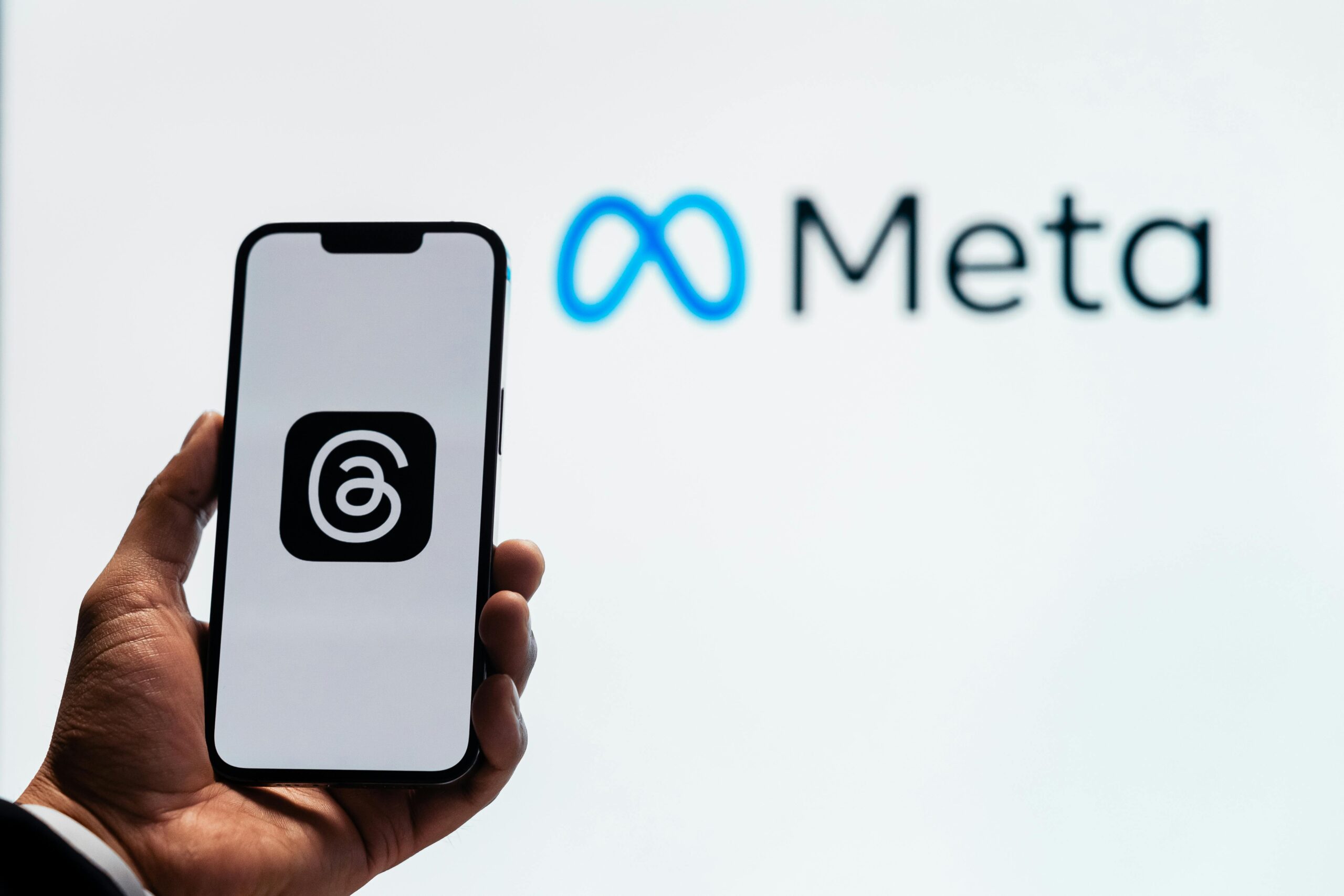 Person holding their phone with the Meta logo in the background