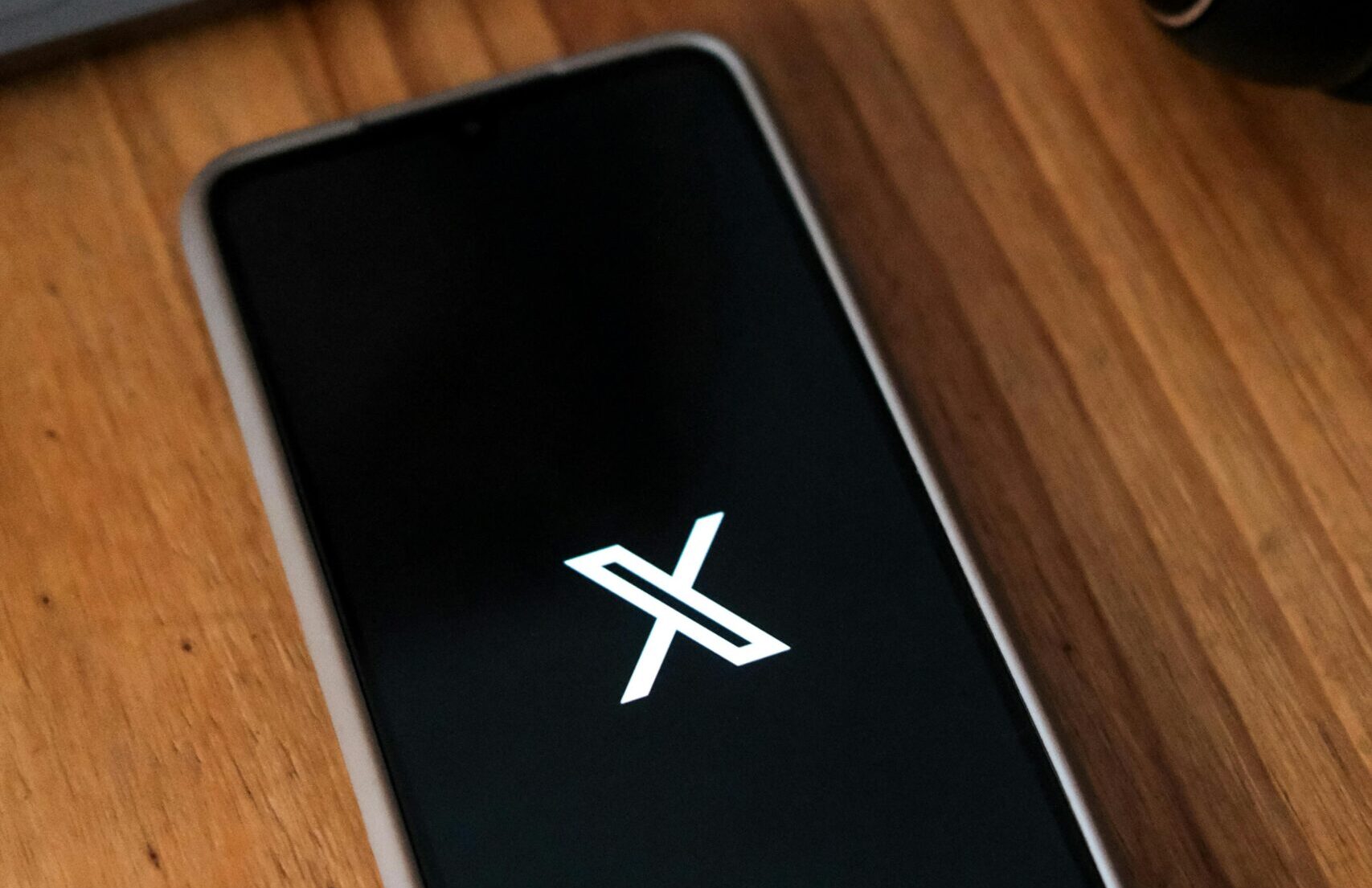 Mobile phone with the X app open on it